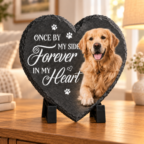 Dark charcoal heart-shaped pet memorial slate with a dog photo on a black stand in a warm living room